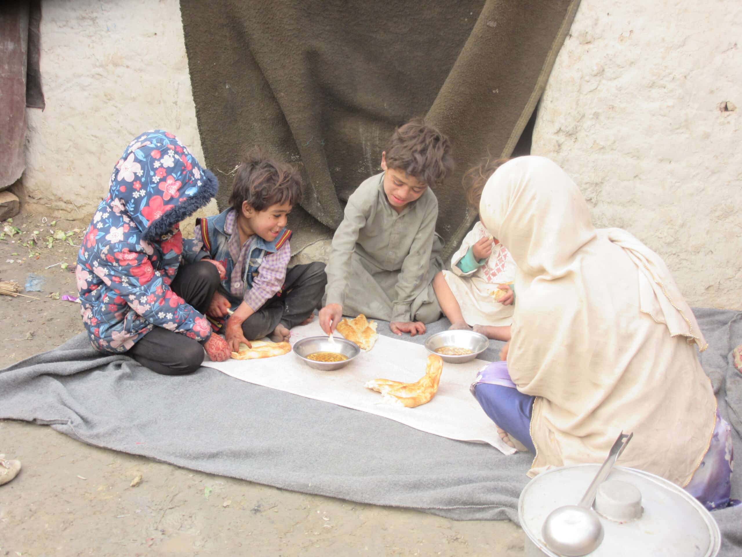 Refugee mother feeding children soy naan and soy qorma